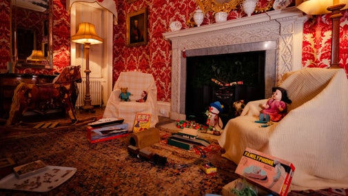 Vintage toys around a fire place, with rocking horse and small train set.